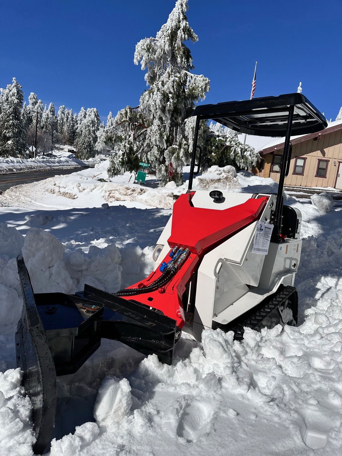 A compact tracked loader working in deep snow