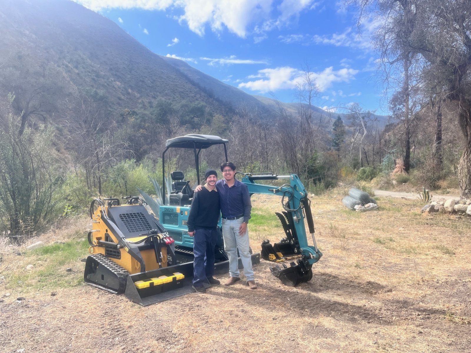 Two team members holding a Leon’s Heavy Equipment banner outside the workshop