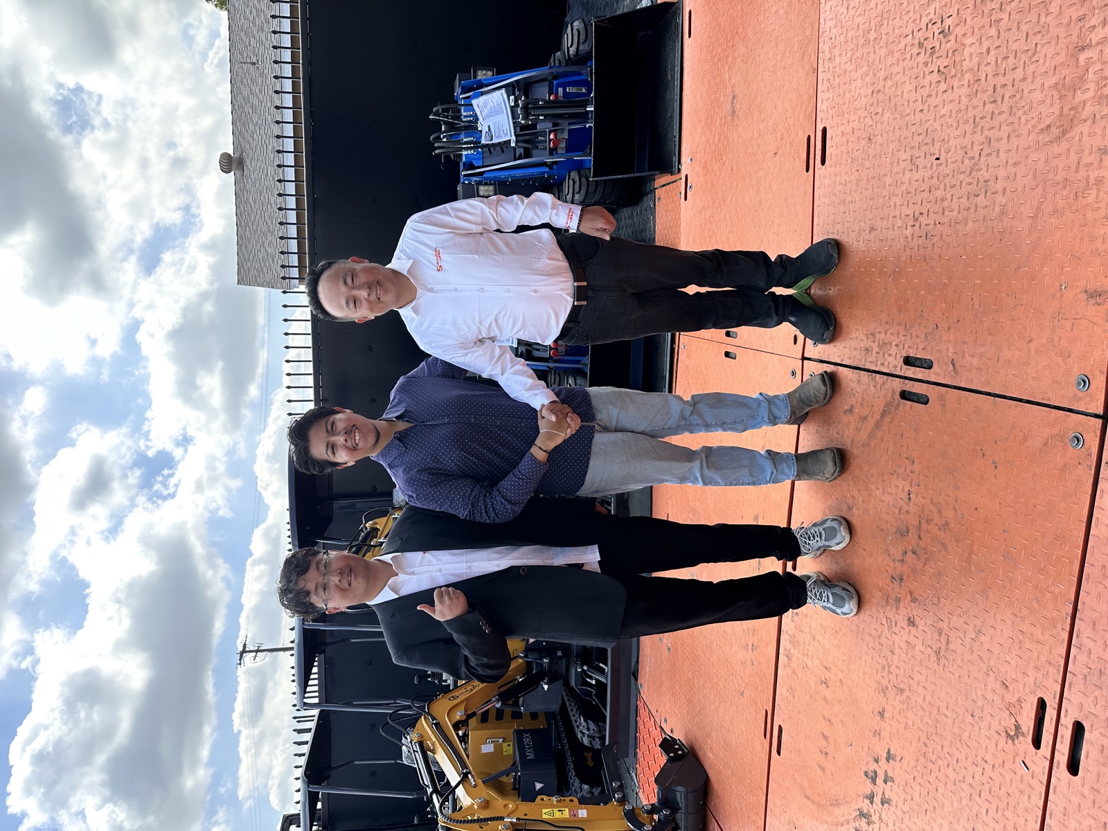 Three people marking a manufacturer partnership with a handshake in the equipment yard